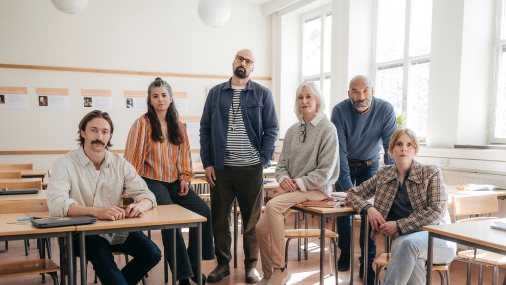 En grupp allvarliga gymnasielärare i ett klassrum.