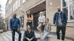 En grupp leende gymnasielärare vid trappen till ingången till en skola.