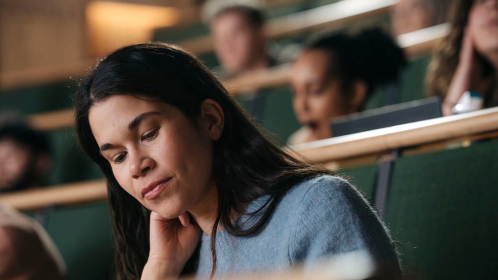 Kvinnlig student under föreläsning i aula vid högskola.