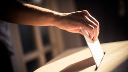 Conceptual image of a person voting, casting a ballot at a polling station, during elections.